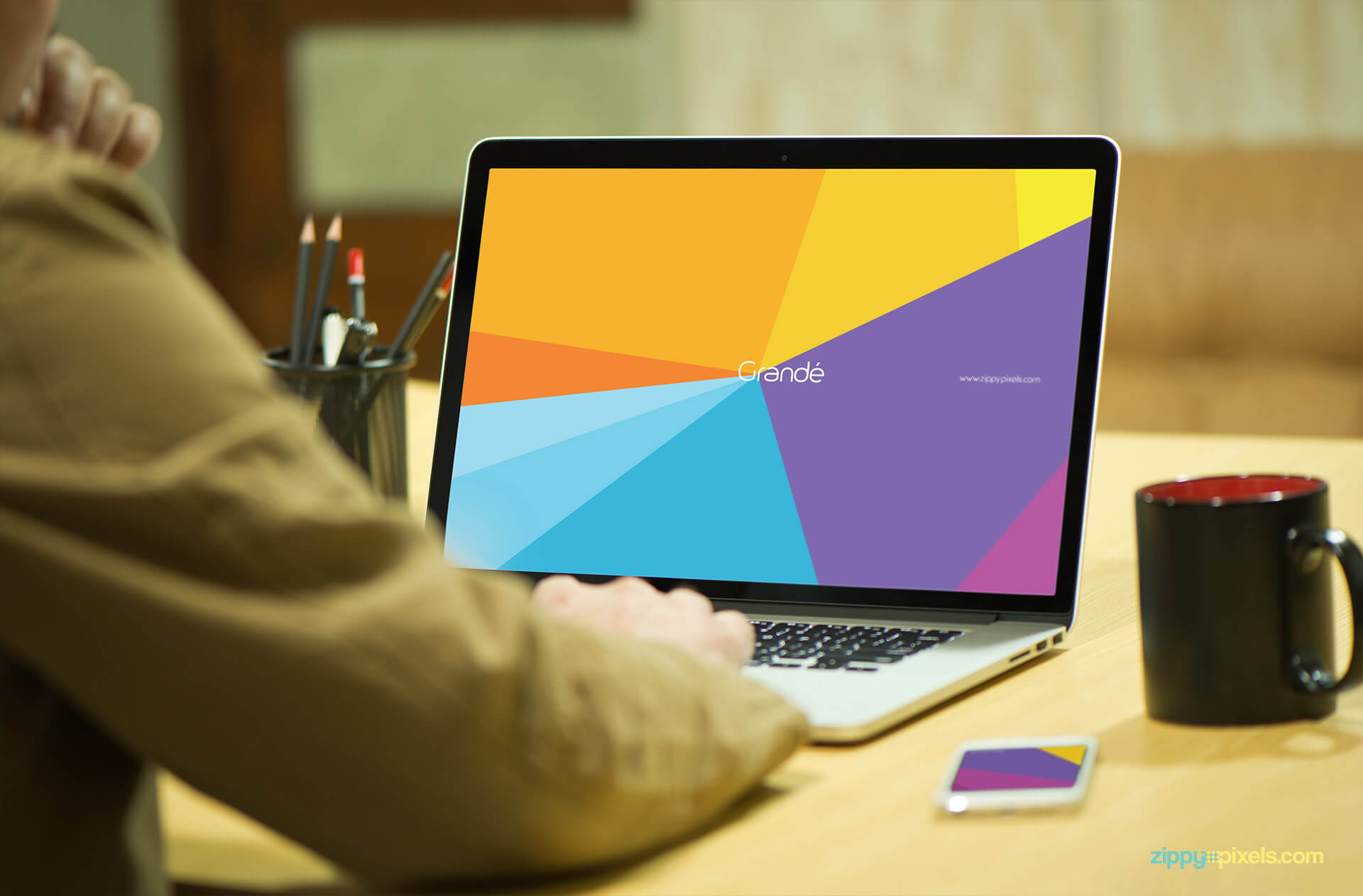 Mockup depicting a Person typing on Macbook with iPhone on the Side