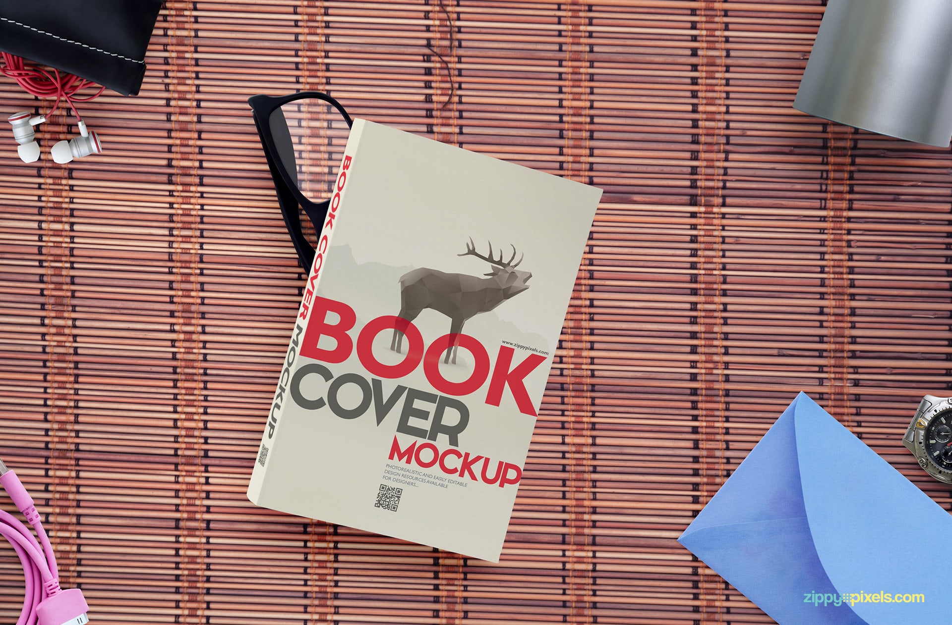 Paperback book lying on top of the glasses, envelope, wristwatch, pen holder, earphones with pouch & usb data cable